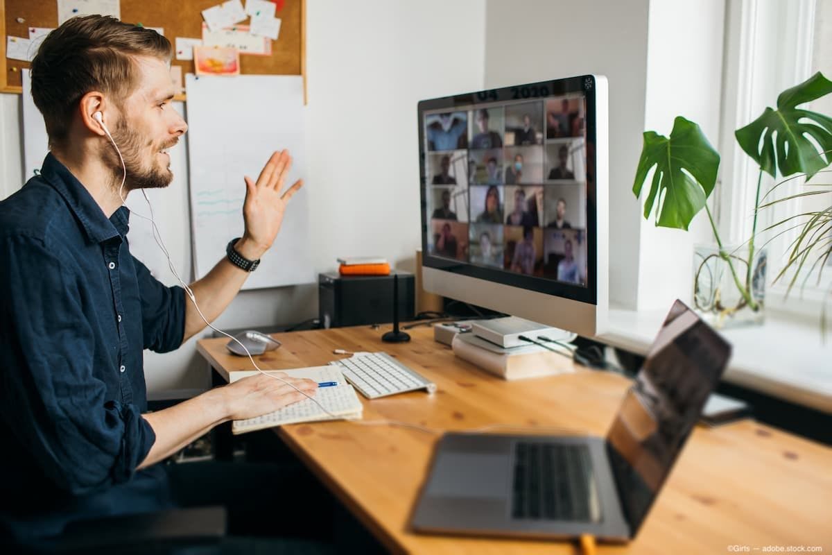 Man waving to computer as he attends a virtual conference (Image credit: AdobeStock/Girts)