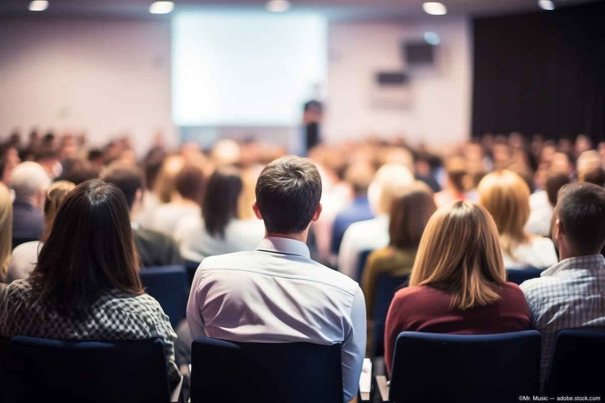 Audience watching a presentation given by burry figure on stage (Image credit: AdobeStock/Mr. Music)