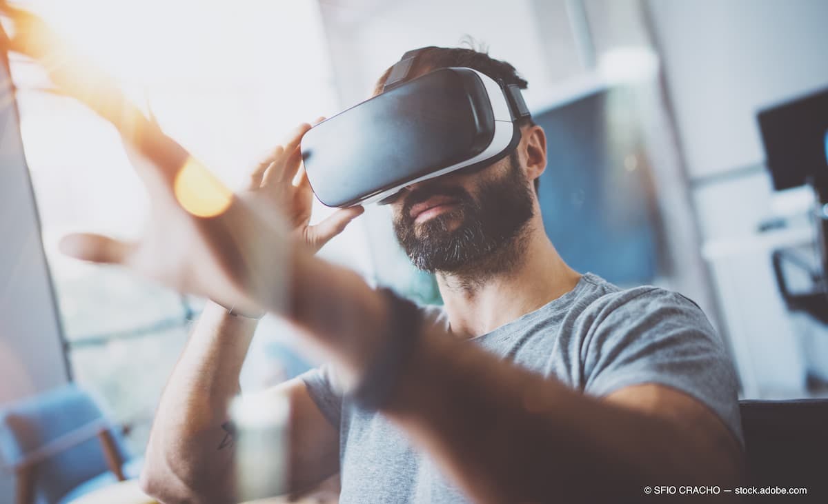 Closeup of bearded young man wearing virtual reality goggles in modern coworking studio. Smartphone using with VR headset. Horizontal, blurred. (Adobe Stock / SFIO CRACHO)